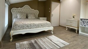 Ein Schlafzimmer mit einem großen Bett, einem Nachttisch, einer Kommode und einer Tür.