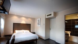 Ein modernes Hotelzimmer mit einem großen Bett, einem Schreibtisch und einem begehbaren Kleiderschrank.