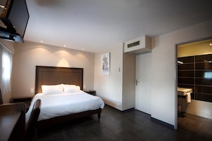 A modern hotel room with a large bed, a desk, and a walk-in closet.