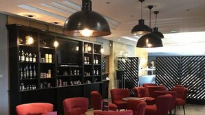 Eine moderne Bar mit roten Stühlen und schwarzen Pendelleuchten.