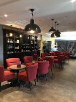 A modern bar area with red chairs and black pendant lighting.
