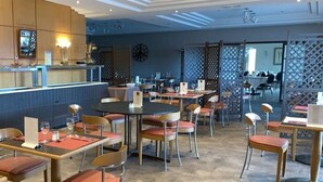 Ein Restaurant mit mehreren Tischen und Stühlen, einer Theke mit Speisekarte und einer Uhr an der Wand.