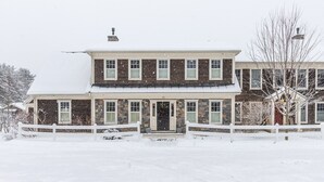 A two-story house with a snow-covered roof and a white picket fence. - High End Townhouse, Centrally Located, to Skiing, Mountain Biking & Rec Path (Stowe)