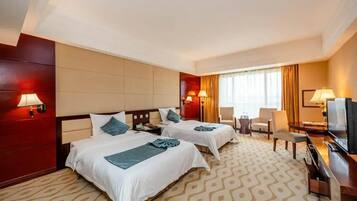 Una habitación de hotel con dos camas, un televisor, un escritorio y una silla.