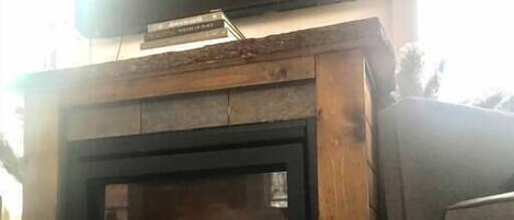 A fireplace with a TV mounted above it, a grey couch to the right, and a fluffy white rug in front.