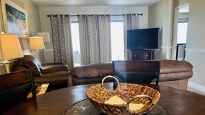 Una sala de estar moderna con una mesa de madera oscura, sofás de cuero, una cesta tejida y un televisor de pantalla plana.
