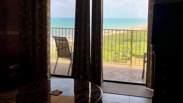 Una habitación con vista a la playa, una silla y una mesa.
