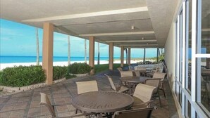 Eine Terrassensitzgruppe mit Tischen und Stühlen mit Blick auf einen Strand.