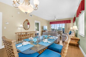 A dining area with a glass table, wicker chairs, and blue cushions.