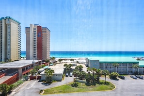 Hotel com estacionamento, vista para a praia e fachada em vermelho e bege.