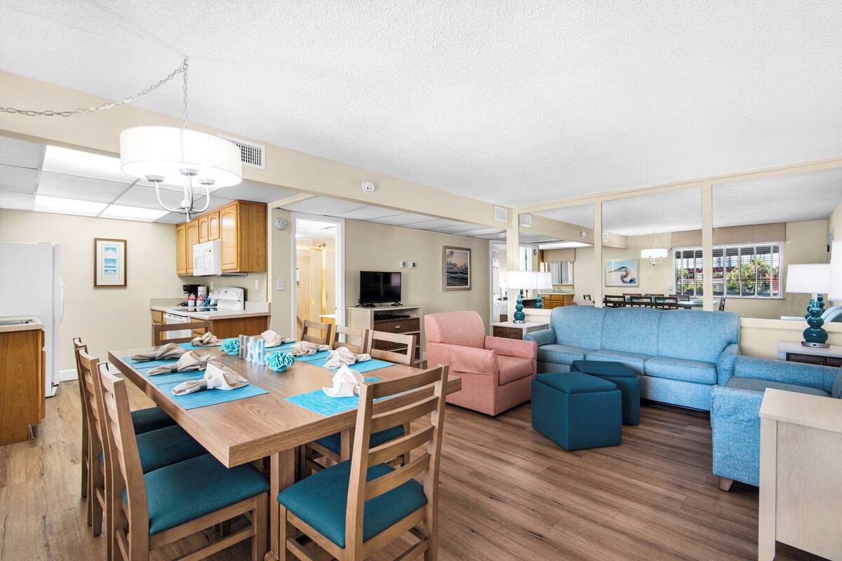 A spacious living area with a dining table, chairs, a sofa, and a television.