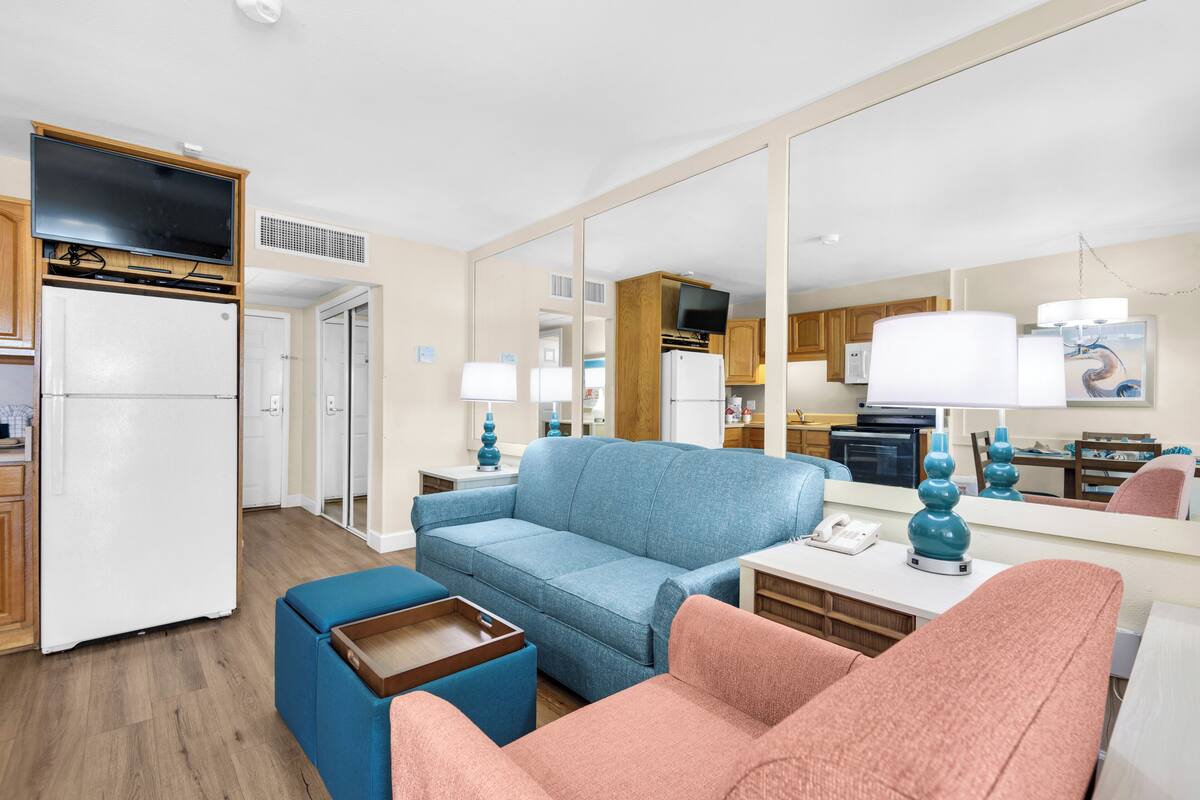 A compact living space with a kitchenette, a sofa, a chair, and a dining table.