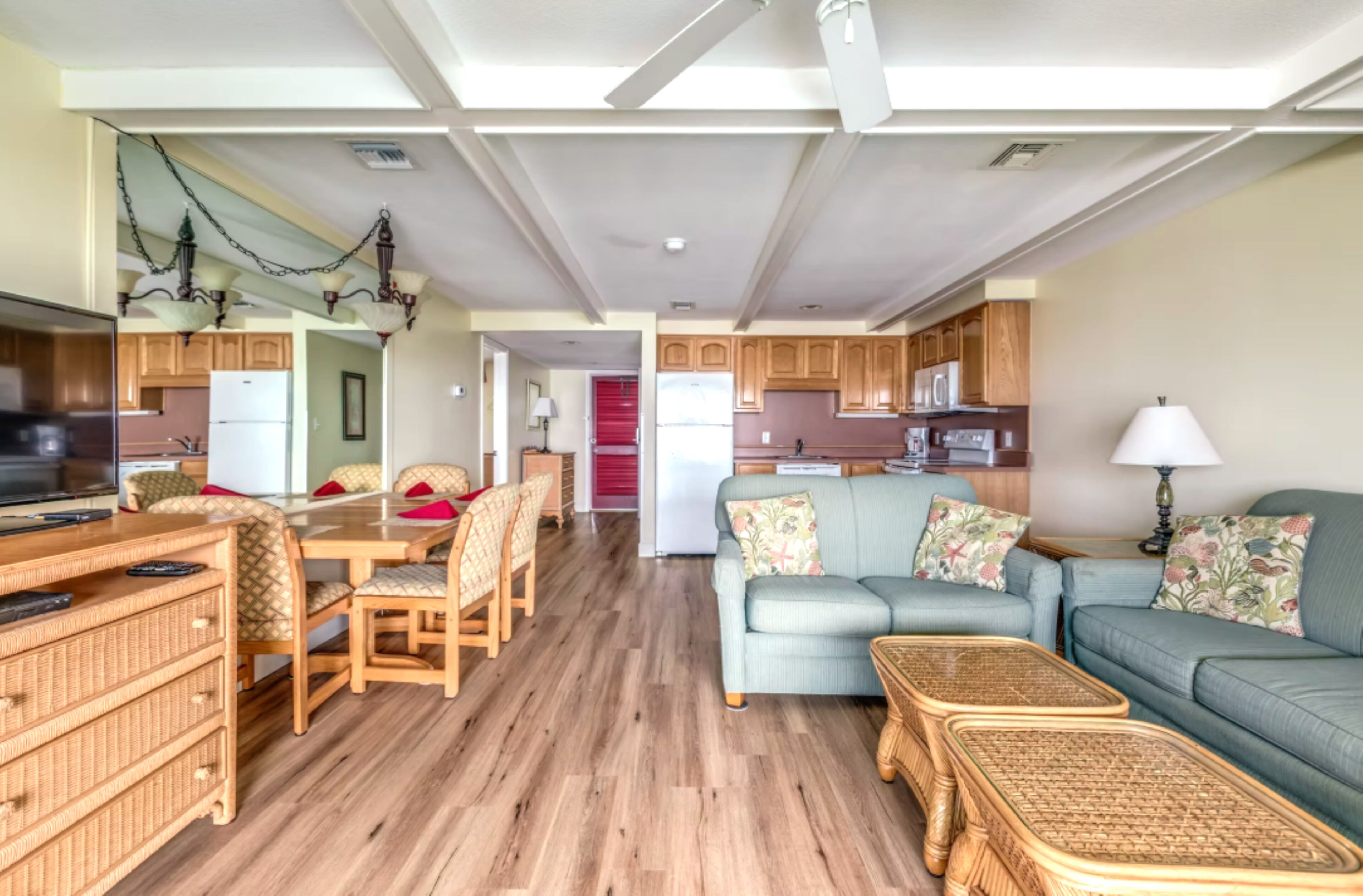 A spacious living area with a dining table, sofas, and a kitchen in the background.