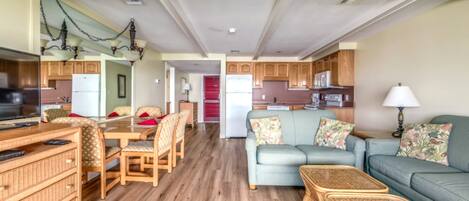 A spacious living area with a dining table, sofas, and a kitchen in the background.