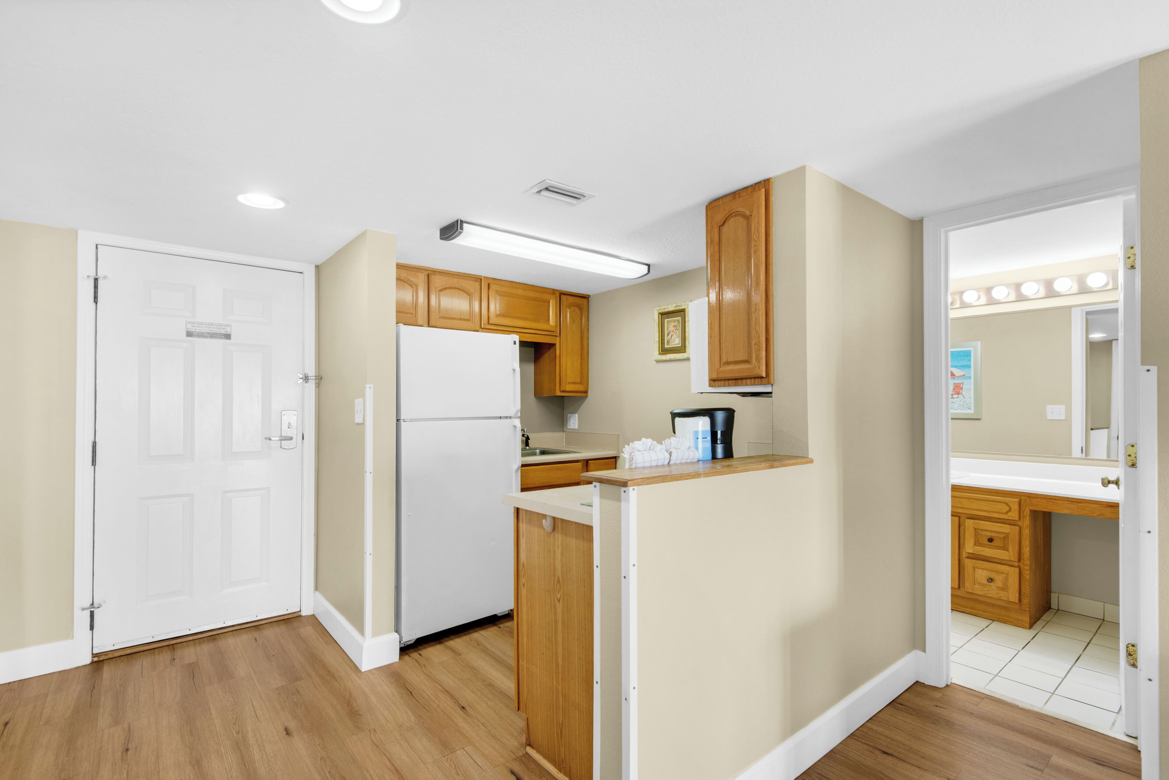 A kitchen with wooden cabinets, a white refrigerator, and a countertop with a coffee maker.