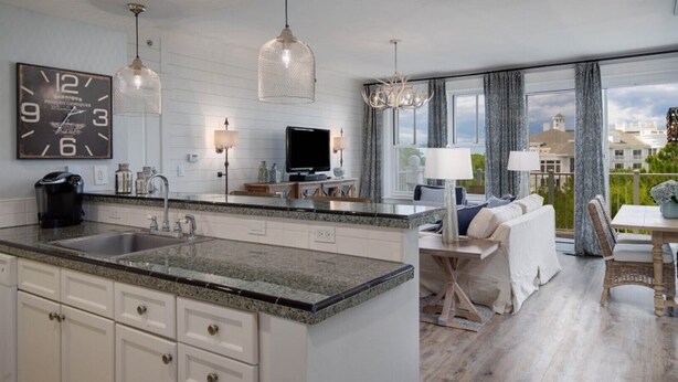 A modern kitchen with granite countertops, a built-in island, and a large clock. - 1 bedroom, 2 Full bath condo in Sandestin  (Miramar Beach)