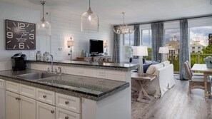 A modern kitchen with granite countertops, a built-in island, and a large clock.
