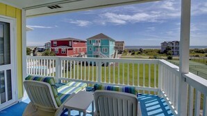 A balcony with white railings and a view of colorful houses and the ocean. - Cozy 2BR condo at Holden Beach, perfect for a family getaway! (Holden Beach)