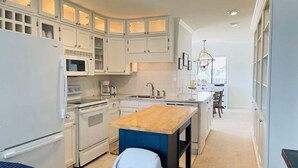 A modern kitchen with white cabinetry, a wooden island, and a view of the city. - Cozy 2BR condo at Holden Beach, perfect for a family getaway! (Holden Beach)