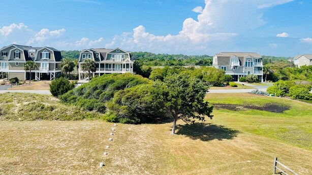 A residential area with multiple houses, a clear sky, and a grassy field. - Cozy 2BR condo at Holden Beach, perfect for a family getaway! (Holden Beach)