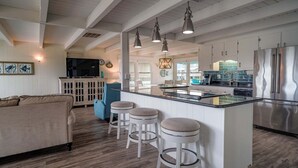 Une cuisine moderne dotée d’un îlot central, de tabourets de bar et d’appareils électroménagers en acier inoxydable.