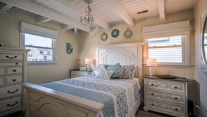 Une chambre à coucher comprenant un lit, une commode, des tables de chevet et un lustre.