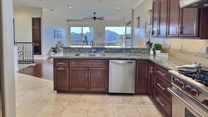 A spacious kitchen with dark wooden cabinets, a stainless steel dishwasher, and a gas stove. - Experience Aloha Avila luxury executive home in San Luis Bay Estates (Avila Beach)