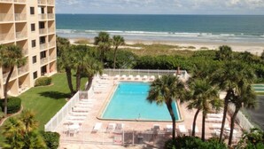 A hotel with a pool, beach view, and palm trees.
