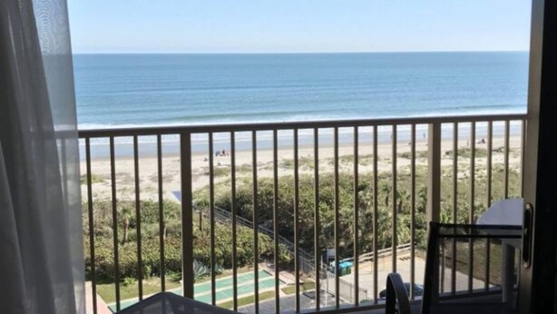 A balcony with a view of the beach and ocean.