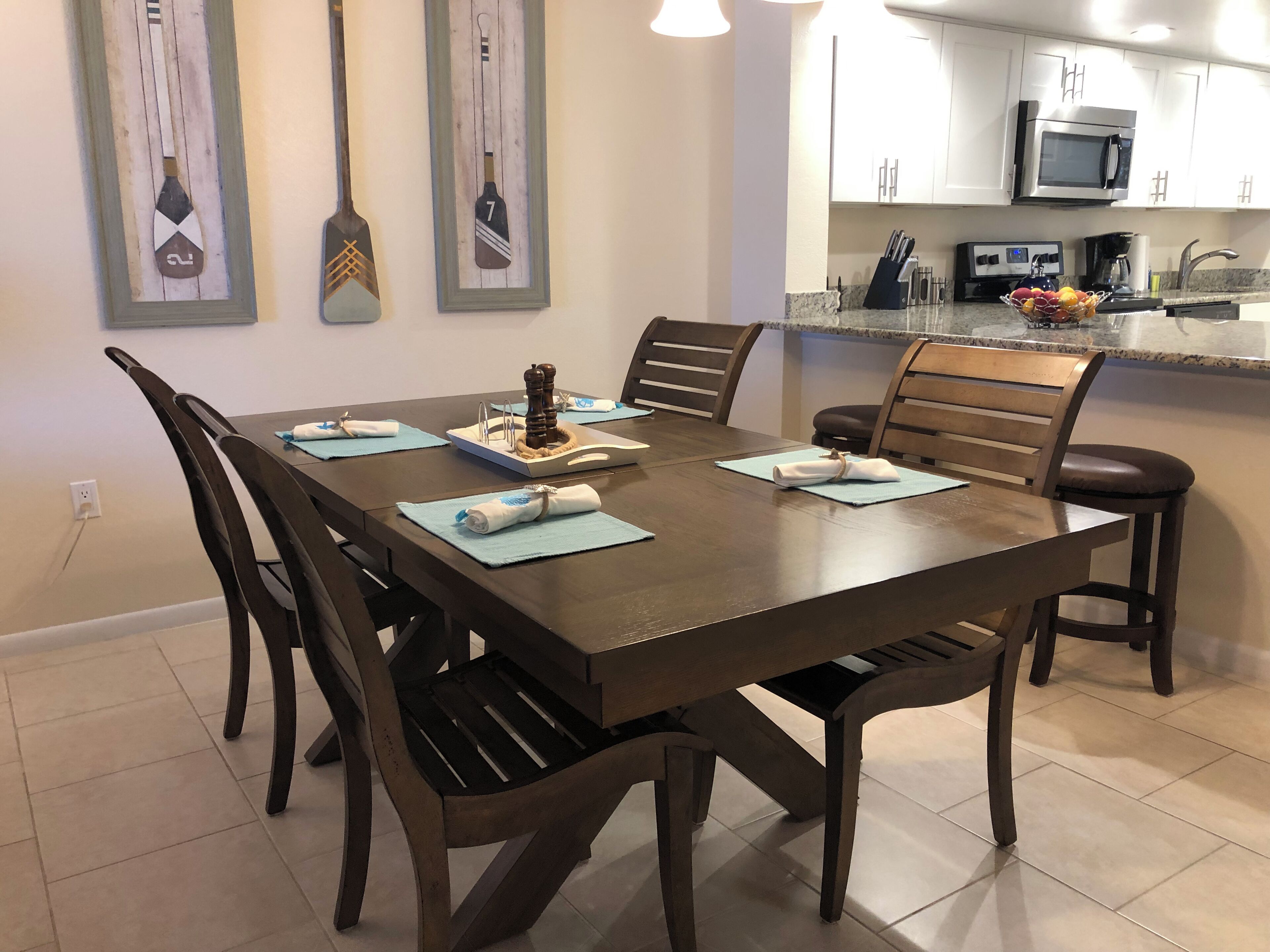 A dining area with a wooden table, chairs, and a kitchen in the background.