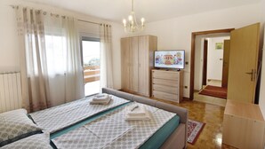 Ein Hotelzimmer mit Bett, Fernseher, Kleiderschrank und Blick ins Freie.