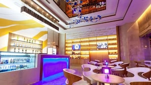 Eine moderne Bar mit verschiedenen Sitzgelegenheiten, einer gut beleuchteten Theke und einer Auswahl an Flaschen in Regalen.