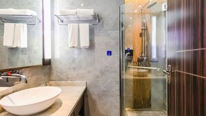 Ein modernes Badezimmer mit einem großen Spiegel, einem weißen Waschbecken und einer Duschkabine.