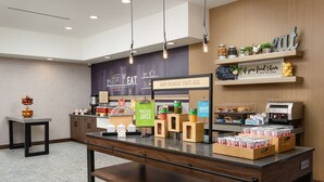 A breakfast area with a counter displaying various food items and a sign that says "Happy breakfast starts here."