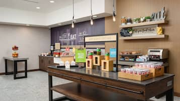 A breakfast area with a counter displaying various food items and a sign that says "Happy breakfast starts here."