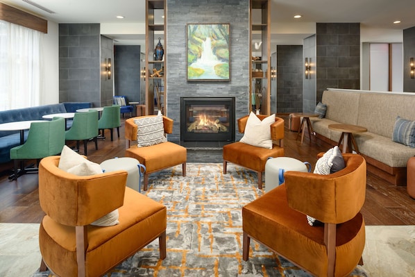 A modern lounge area with a fireplace, comfortable seating, and a large painting above the fireplace.