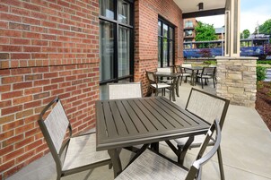 An outdoor patio with a brick wall, a table with chairs, and a stone wall.