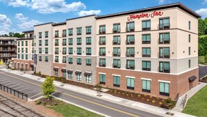 A Hampton Inn hotel with a modern design, multiple floors, and a parking lot.