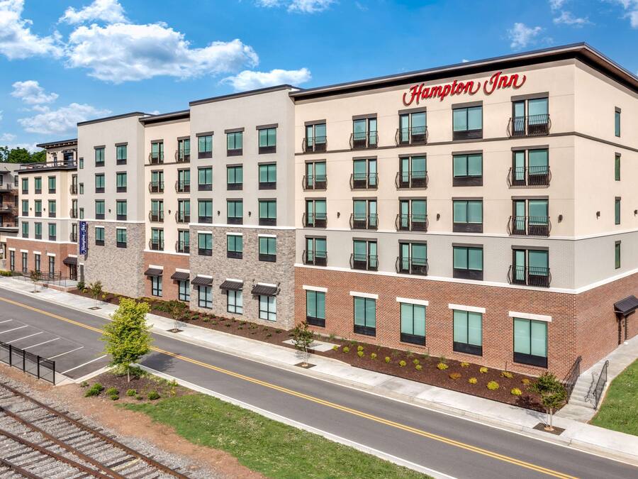 A Hampton Inn hotel with a modern design, multiple floors, and a parking lot.