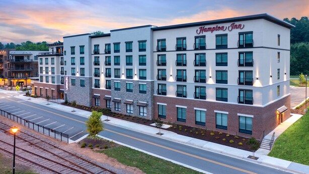 A Hampton Inn hotel with a modern design, featuring a flat roof and multiple balconies.