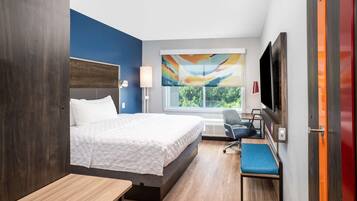 Una habitación de hotel moderna con una cama grande, un escritorio y una televisión.