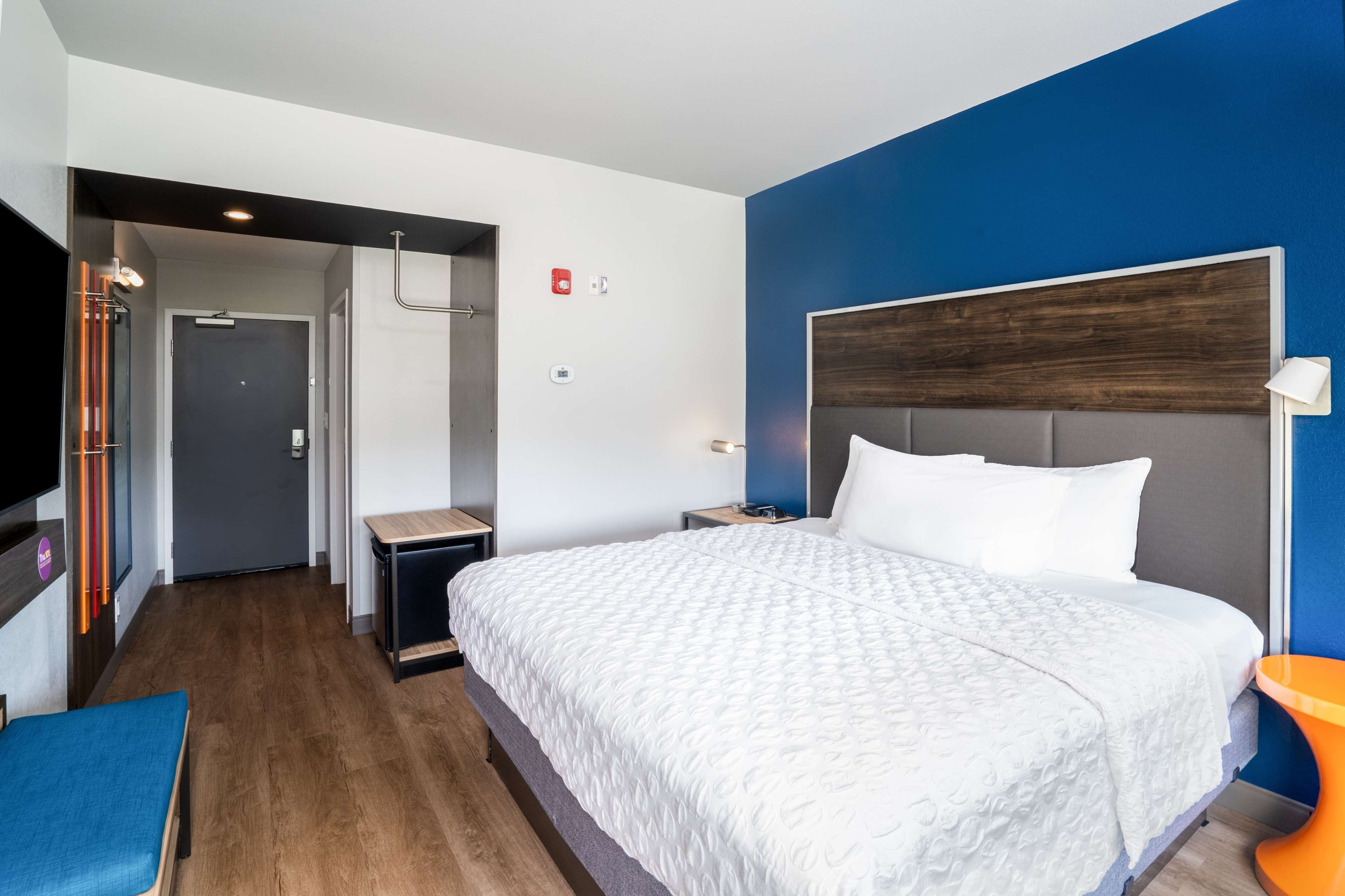 A modern hotel room with a large bed, a desk, and a TV.