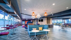 A modern lounge area with seating, tables, and a large window offering a view. - Tru by Hilton North Little Rock (North Little Rock)