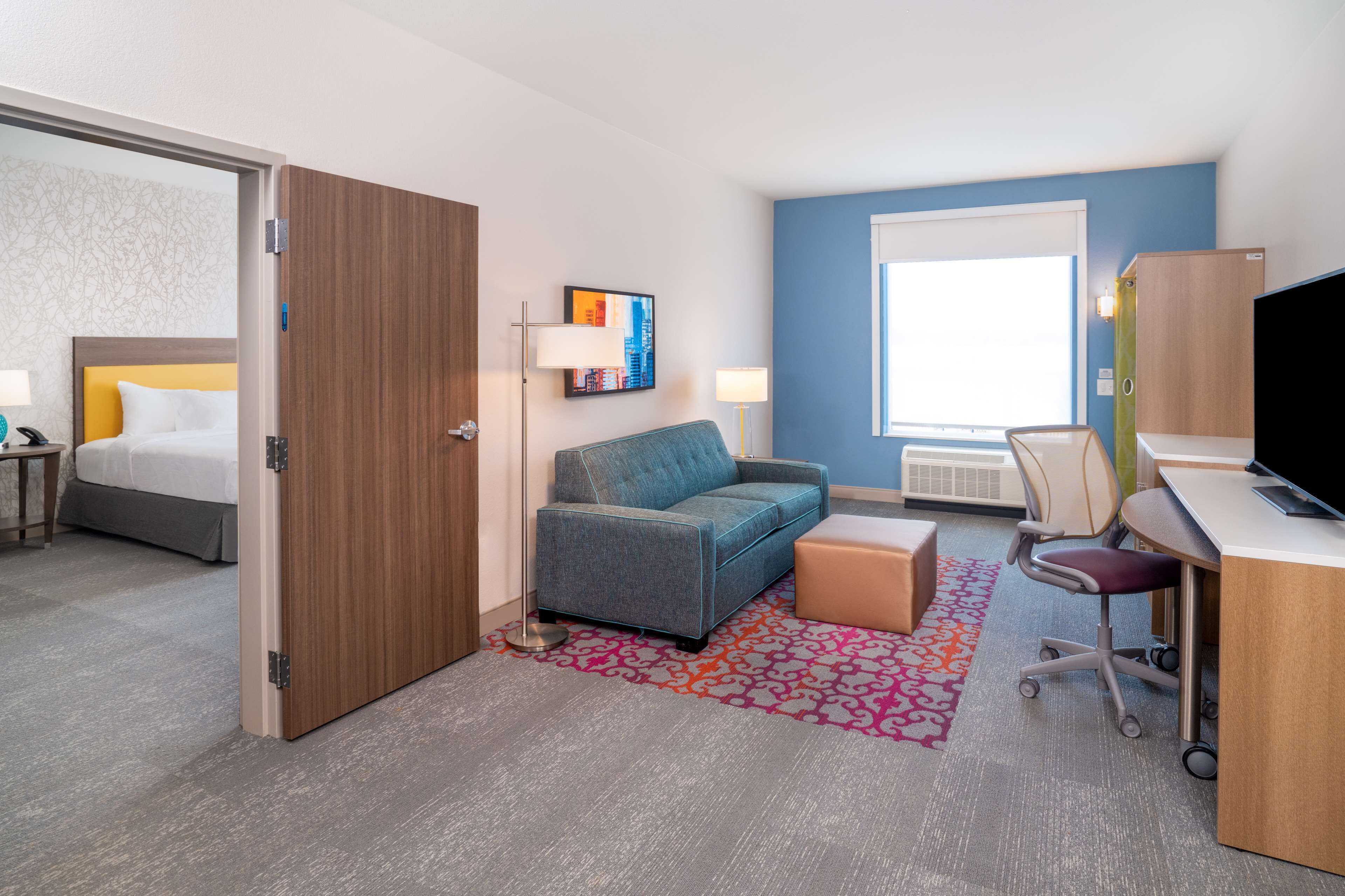 A hotel room with a bed, a sofa, a desk, and a TV.