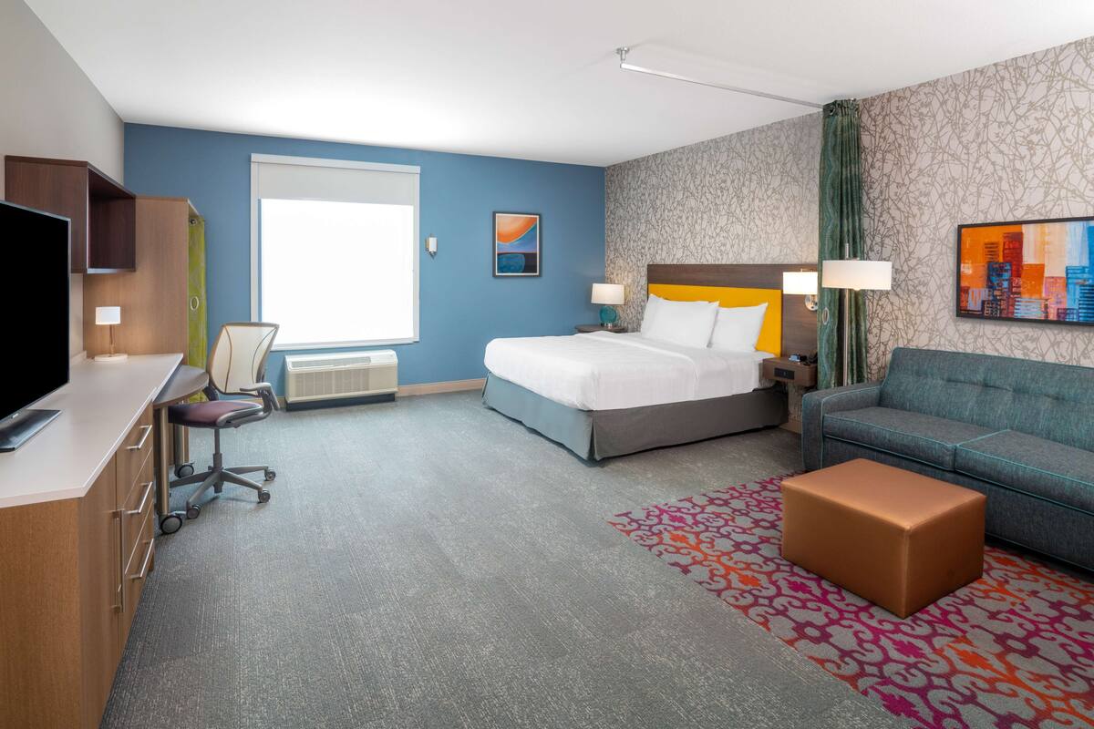 Una habitación de hotel con una cama, un sofá, un escritorio y un televisor.