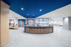 Un área de recepción moderna con un mostrador curvo, un mural grande en la pared y un piso de baldosas impecables.