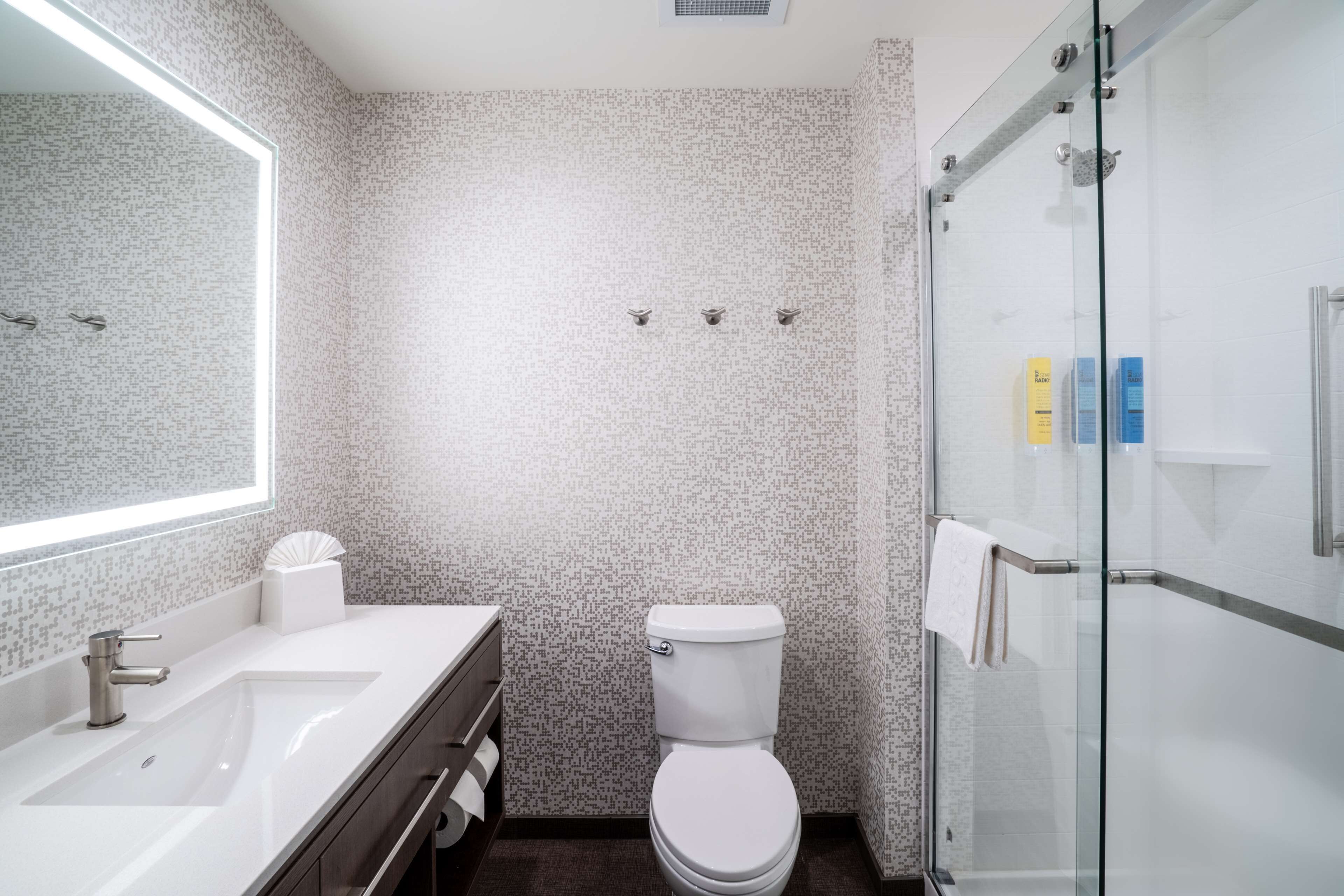 A modern bathroom with a white sink, toilet, and glass shower enclosure.