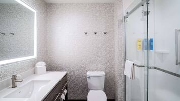 A modern bathroom with a white sink, toilet, and glass shower enclosure.