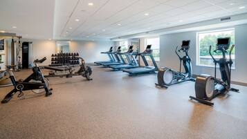 Un gimnasio con cintas de correr, bicicletas estáticas y máquinas de remo.