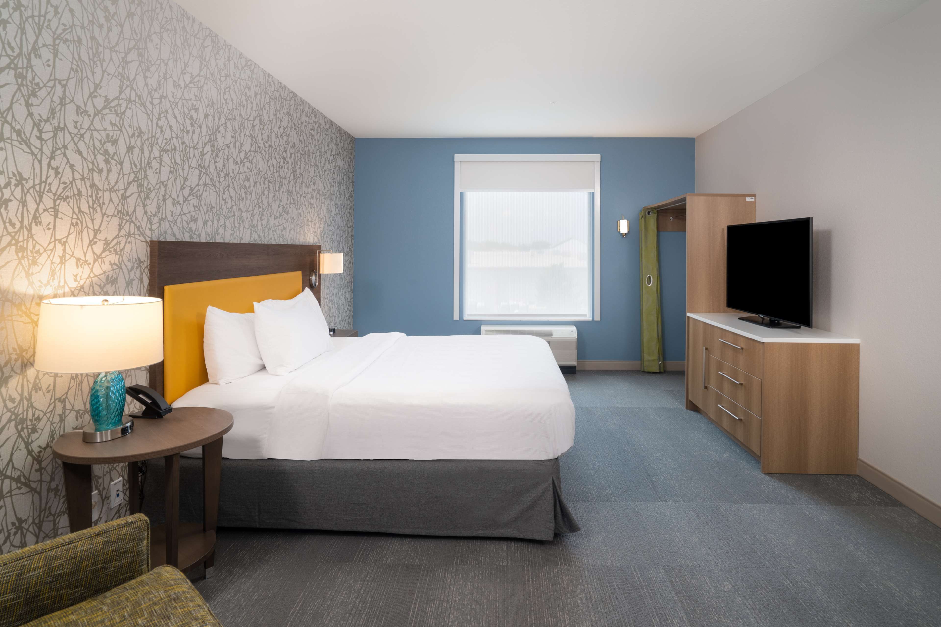 Une chambre d’hôtel avec un lit, une télévision, un bureau avec une lampe et une fenêtre.